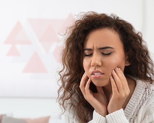 woman in need of emergency dentistry holding jaw