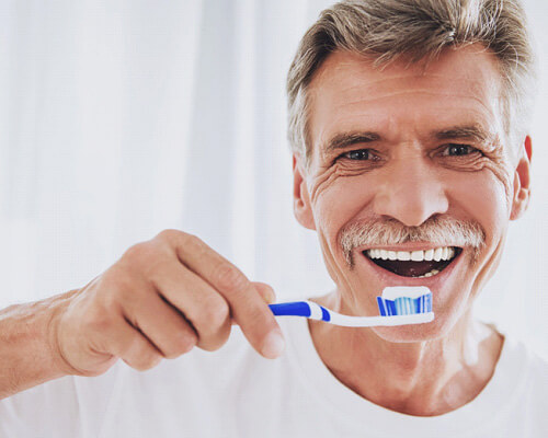 man with dentures holding a toothbrush