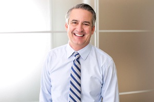 smiling elderly man wearing a light blue dress shirt and tie 