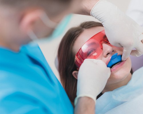 Dentist placing fluoride on young girl's teeth