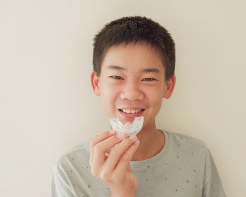 Child smiling while holding mouthguard