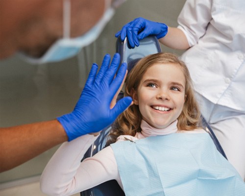 Child smiling and giving dentist a high five