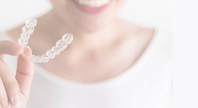 Person holding a clear aligner in their hand