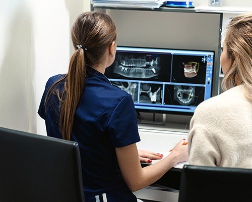 Dentist and team  member looking at digital dental x-rays