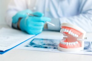 A closeup of dentures on a table while a dentist works nearby