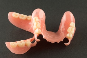 Two acrylic partial dentures resting against dark background