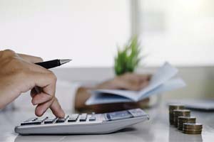 Man calculating price of dentures in Bedford with calculator