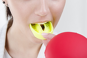 Woman placing a mouthguard into her mouth