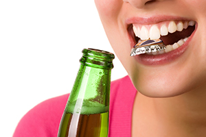 Woman holding bottle cap with her mouth and holding beverage