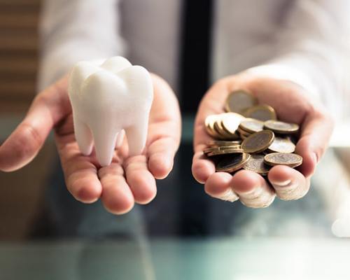person holding fake tooth in one hand and coins in the other