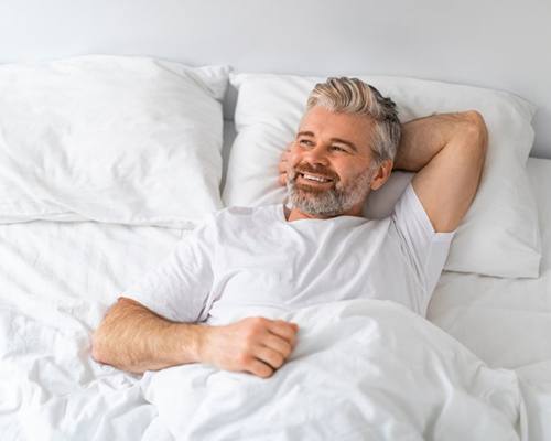 a man smiling and comfortable in bed