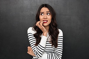 A young female bites her nails and appears worried in Bedford