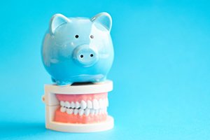 light blue piggy bank sitting on top of a set of false teeth 