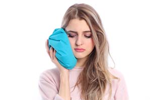 woman holding ice pack against jaw