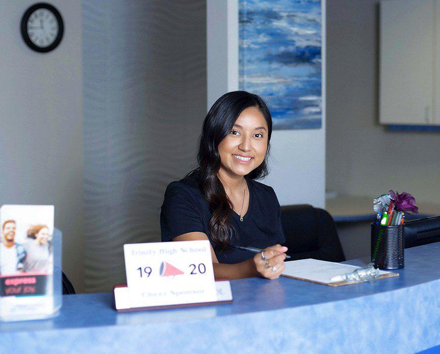 Smiling Bedford dental team member sitting at front desk