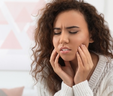 Woman holding both sides of her face in pain