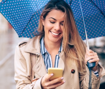 Woman under an umbrella looking at phone