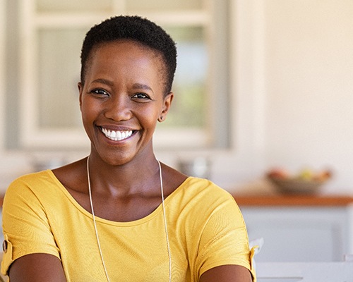 Woman in yellow shirt smiling at home
