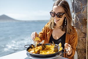 Smiling woman enjoying meal at restaurant on the water