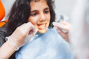 Dentist putting clear aligner on teenage girl