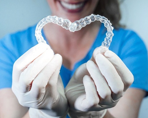 dental team member holding two aligners in the shape of a heart