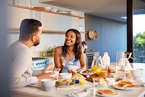 Couple smiling at each other while eating in kitchen