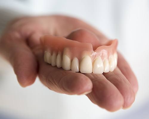 Hand holding a full denture