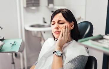 Woman in need of emergency dentistry holding jaw