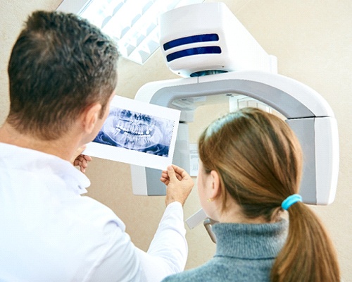 Dentist showing dental X-ray to female patient