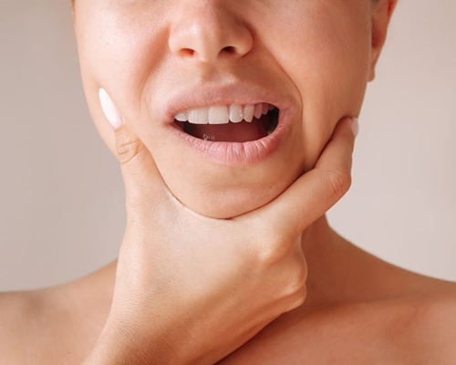 Woman holding her jaw, experiencing TMJ pain
