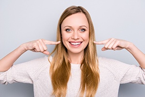 Woman pointing to her new smile with veneers