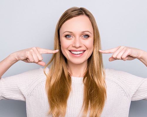 Woman pointing to her straight, white teeth