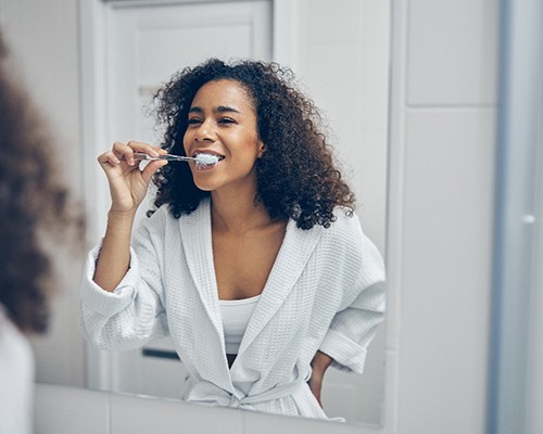 Woman smiling while brushing her teeth