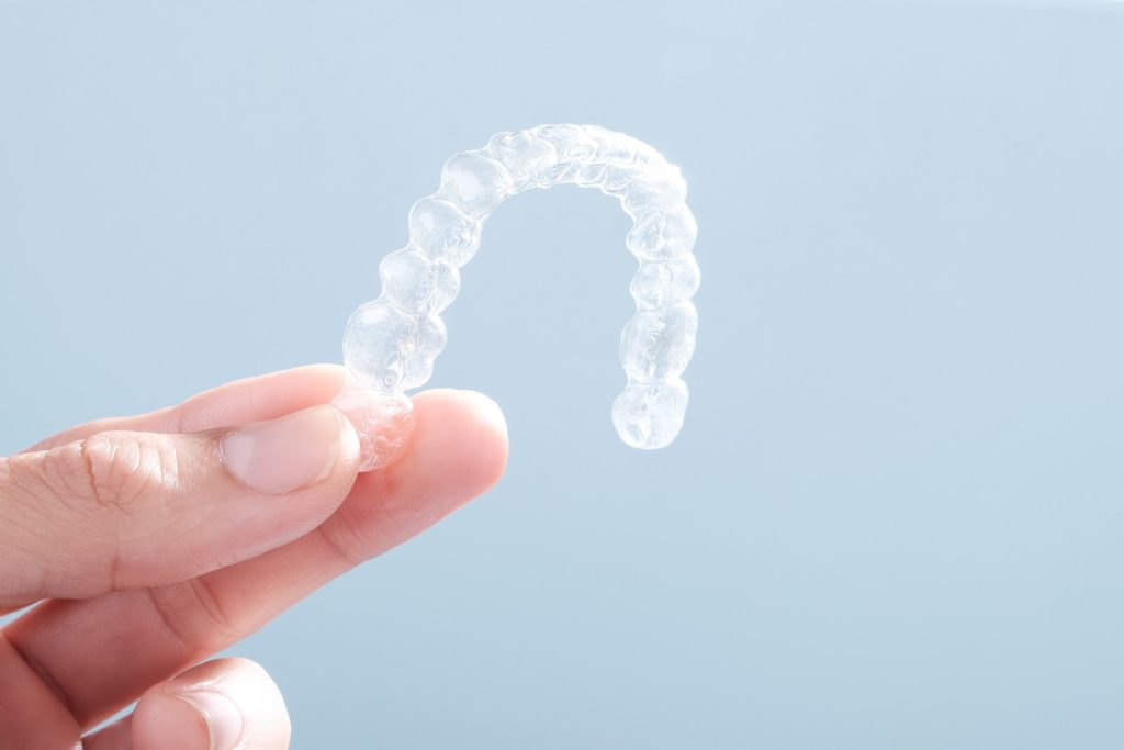 Patient holding up Invisalign aligner