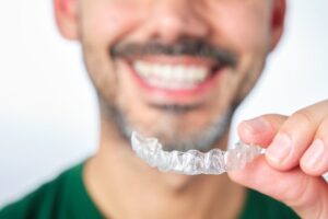 Man smiling while putting in his Invisalign